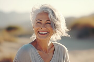 Portrait of a happy senior woman smiling at the camera on the beach