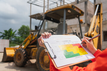 Wall Mural - the operation supervisor is using ballpoint pen to marking on the risk assessment matrix form, to in