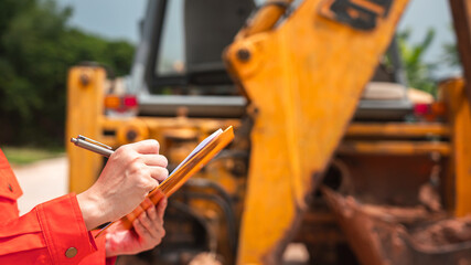 Wall Mural - a mechanical engineer is using checklist form to verify the excavator or earthmover machine (as back