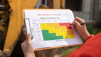 Wall Mural - the operation supervisor is using ballpoint pen to marking on the risk assessment matrix form, to in