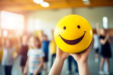 Child holding yellow ball with happy smiling face. Concept for happiness in schools or daycares