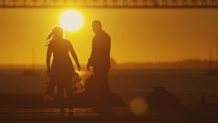 Wall Mural - Couple silhouette against sunset and bridge.