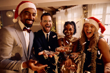 Cheerful friends throwing confetti and having fun on New Year's party.