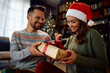 Happy woman opens gift box from her boyfriend on Christmas day at home.