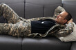 © Angelov - Young African American military man lying down on sofa and thinking of something at home.