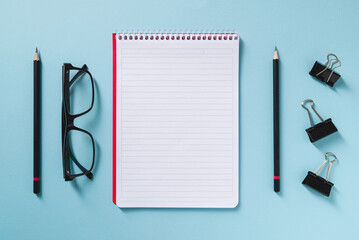 Wall Mural - Top view of empty notebook, glasses and pen on blue office desk