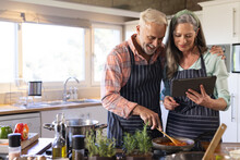 Happy Senior Caucasian Couple Cooking Dinner, Using Tablet In Kitchen, Copy Space