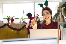 Happy Caucasian Casual Businesswoman Wearing Reindeer Antlers Having Laptop Video Call In Office