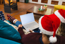 Caucasian Couple In Christmas Hats Having Laptop Video Call On Couch, Copy Space Screen