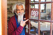 © Wavebreak Media - Happy biracial senior business owner with long beard showing shop sign to open