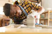 Focused African American Potter Working On Clay Vase Using Potter's Wheel In Pottery Studio