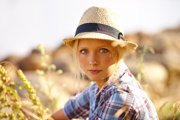 Serious, portrait and young woman in nature with straw hat sitting in outdoor garden for fresh air. Beautiful, fashion and female person from Australia in the forest, woods or field with casual style