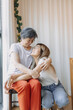 © Suthida - Happy Asian Thai mother and daughter looking at each other with love, cuddle hugging while mom sitting on chair at home, good family relationship.