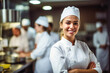Young and pretty woman chef in the kitchen, smiling in front of the camera