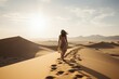 Back view of a barefoot woman walking on a desert dune