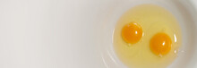 Top View. Two Yellow Raw Fresh Egg Yolks And In A White Plate. Horizontal Banner With Copy Space For Recipe Text. Concept Of Healthy Food, Cooking In The Kitchen. Copyspace. Happt Easter Background