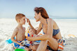 © Marko Geber - Happy young mother applying sunscreen to her son at the beach