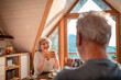 © Marko Geber - Senior woman laughing over morning coffee with her partner in a sunlit cabin