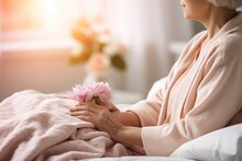 Senior Woman Holding A Pink Flower In A Retirement Home, Closeup On Hands