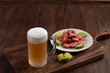 Beer mug on wooden board with portion of fried chicken and sausage