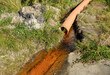 A waste water drainage pipe with flowing water polluting the environment