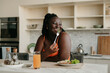 Beautiful curvy African woman enjoying healthy food for lunch at the domestic kitchen