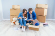 © gorynvd - Couple have a discussion about design of their new home sitting on the wooden floor between many cardboard boxes. Beautiful young stylish couple in love planning home design for their new bought flat.