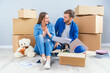 © gorynvd - Couple have a discussion about design of their new home sitting on the wooden floor between many cardboard boxes. Beautiful young stylish couple in love planning home design for their new bought flat.