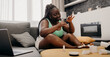 © gstockstudio - Beautiful plus size African woman painting toenails while sitting on the comfortable couch at home