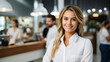 © Uwe - Smiling, young and attractive saleswoman, cashier serving customers with blurred shop in the back, with empty copy space