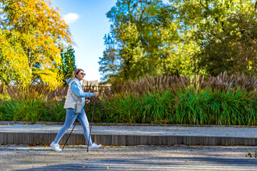 Wall Mural - Nordic walking - mid-adult woman exercising in city park
