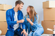 © gorynvd - Couple taking a break on moving day, sitting on floor in new apartment celebrating with champagne surrounded by cardboard boxes.