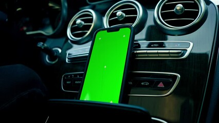 close-up of a phone with a green screen display stands on the dashboard in a luxurious auto connection technology