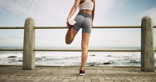 Woman, Stretching Legs And Ocean Promenade For Warm Up, Training And Healthy Muscle To Stop Injury. Runner Girl Back, Exercise And Workout Outdoor For Wellness By Sea, Fence Or Challenge For Fitness