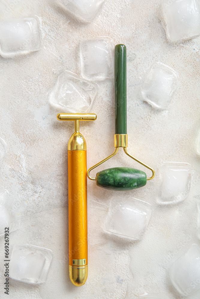 Different face massage rollers with ice cubes on light background