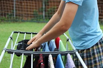 Teenager hanging clothes on drying rack to help out with household chores