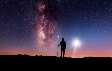 Wall Mural - silhouette of a hiker standing on the hill, on the milky way galaxy background.