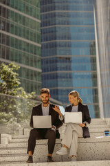 Wall Mural - Focused businessman and businesswomen working outdoor on laptop with new startup project