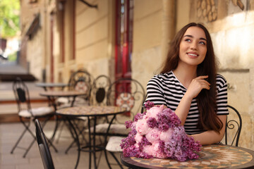 Wall Mural - Beautiful woman with bouquet of spring flowers in outdoor cafe, space for text