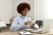© New Africa - Beautiful young woman using laptop and drinking coffee at wooden desk in room