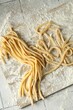 Raw homemade pasta and flour on light tiled table, top view
