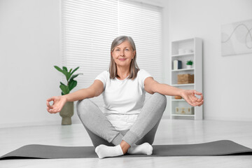 Poster - Happy senior woman practicing yoga on mat at home