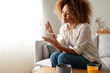 © Daniel - Young relaxed pensive African American woman eating healthy breakfast sitting on the couch. Copy space.