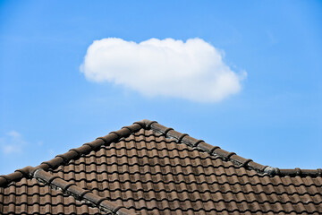 Canvas Print - grey roof tile of house on blue sky and white single cloud background