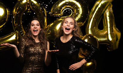 Wall Mural - Happy gorgeous girls in stylish sexy party dresses holding gold 2021 balloons, having fun at New Year's Eve Party.