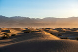 Fototapeta  - Sand dunes of Death Valley, at dawn, with high mountains in the horizon, hazy dusty sky. California, USA