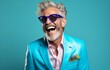 Lively portrait of a silver-haired man in a vibrant blue blazer, laughing heartily against a turquoise backdrop. Ideal for corporate, fashion, or lifestyle campaigns.