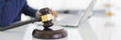 Lawyer woman typing business contract and law agreement on laptop with wooden judge gavel on desk