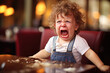 Unhappy toddler boy having a temper tantrum in cafe or restaurant