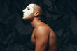 Behind curtains concept. Arty portrait of circus performer over black wrinkled background. White mask on face. Muscular body and perfect tan. Close up. Text space. Studio shot